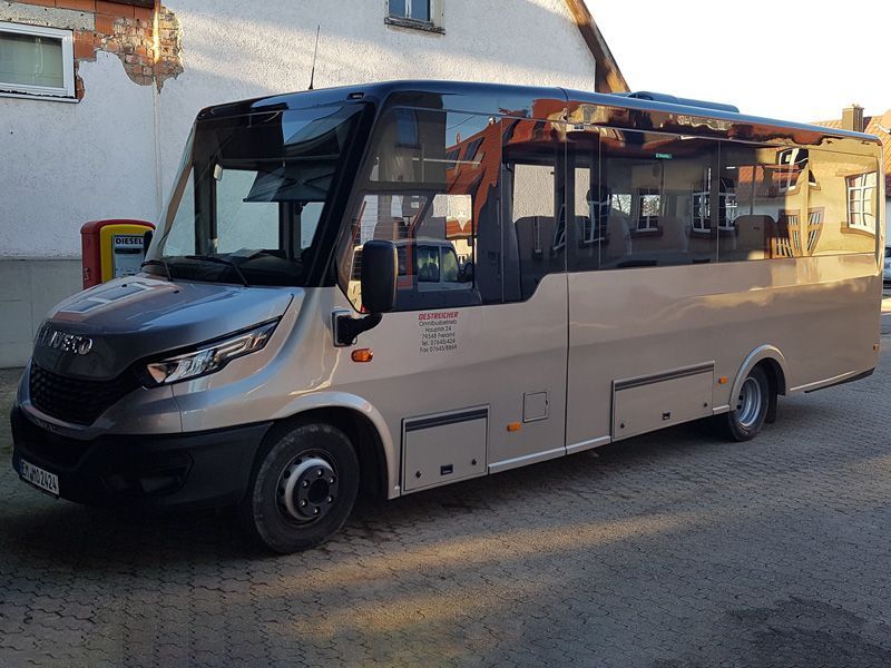 Vor einem Gebäude parkt ein kleiner Bus.