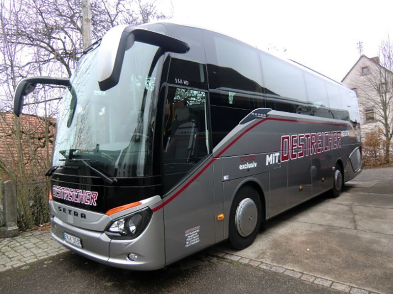 Ein großer silberner Bus steht auf einem Parkplatz.