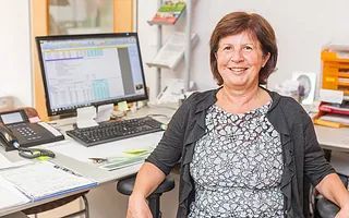 Eine Frau sitzt an einem Schreibtisch vor einem Computer.