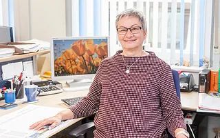 Eine Frau sitzt an einem Schreibtisch vor einem Computer.