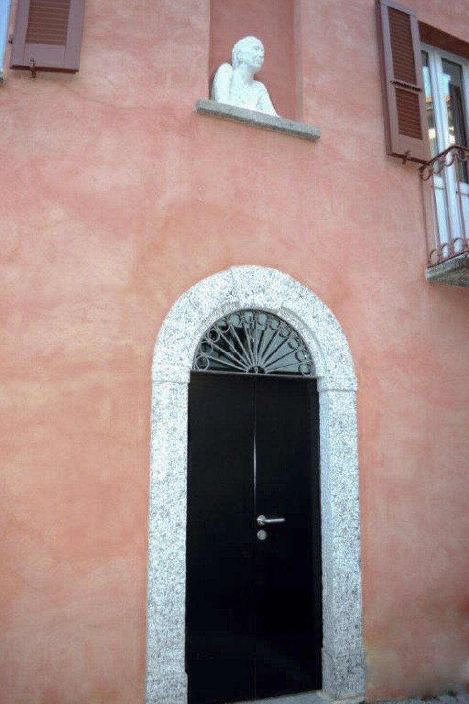 facciata di edificio storico con statua e portone ad arco