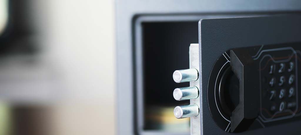 Coffre-fort noir ouvert, laissant apparaître trois verrous argentés et un clavier numérique.
