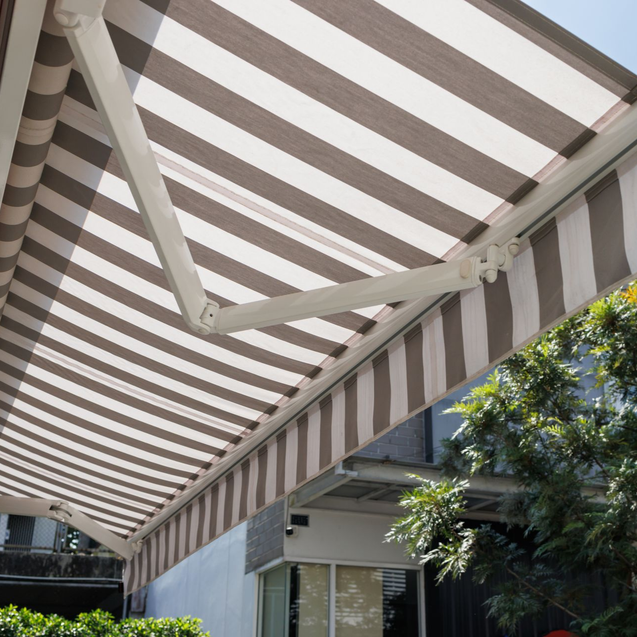 Auvent rayé marron et blanc s'étendant sur la zone extérieure d'un bâtiment.