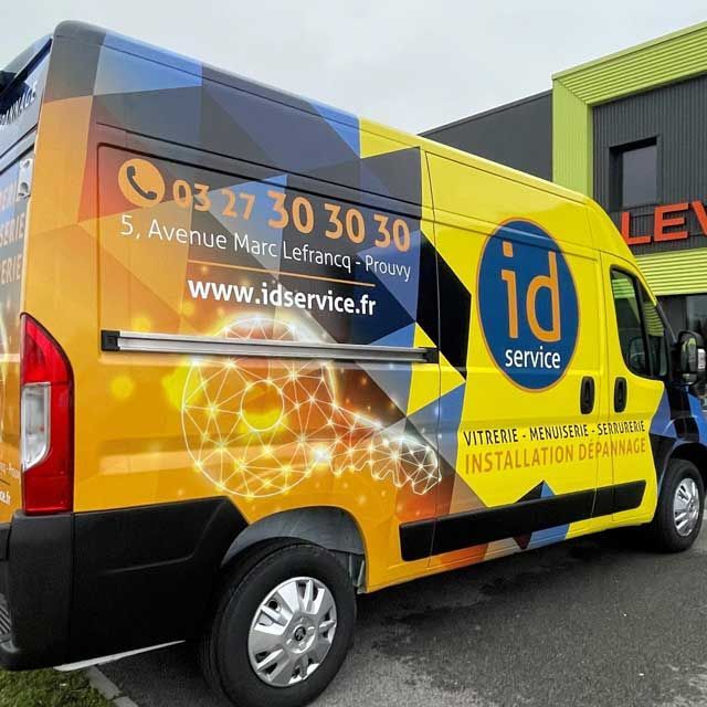 Fourgonnette jaune avec logo « id service », numéro de téléphone et site Web sur le côté.