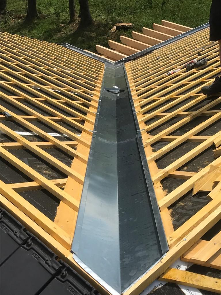 Une gouttière métallique installée sur la charpente en bois d'un toit en construction.