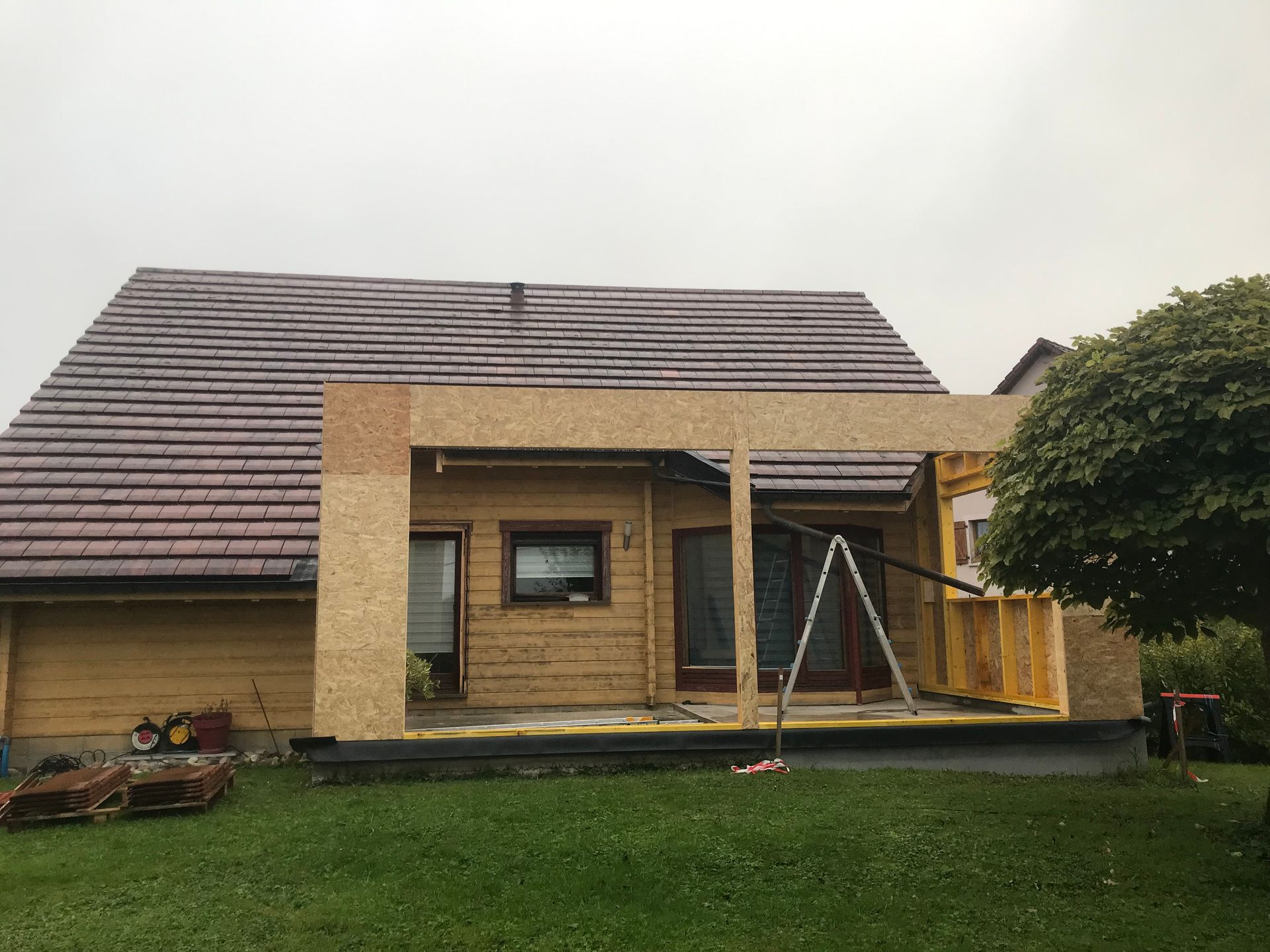 Une maison en rénovation avec une extension en bois nouvellement construite, adossée à l'arrière.