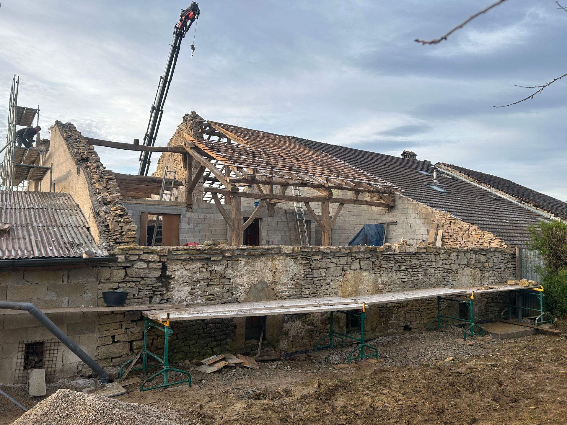 Une grue travaille sur le toit d'un bâtiment en pierre en cours de restauration, tandis que des échafaudages longent les murs extérieurs.