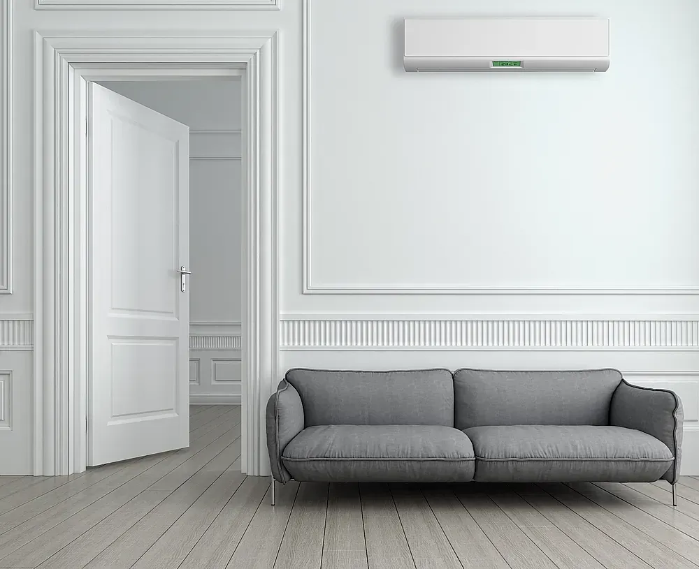 Una sala de estar con un sofá y un aire acondicionado en la pared.