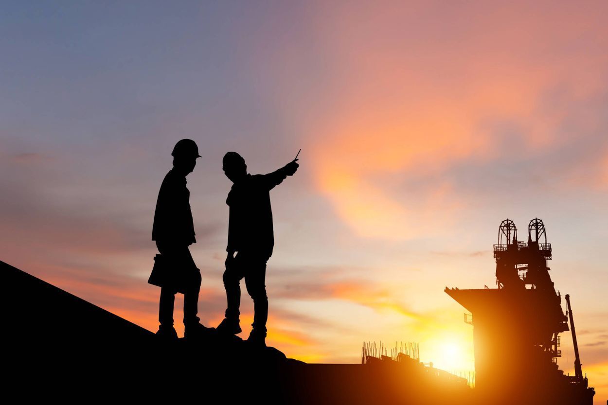 Dos hombres están parados en la parte superior de un edificio al atardecer.