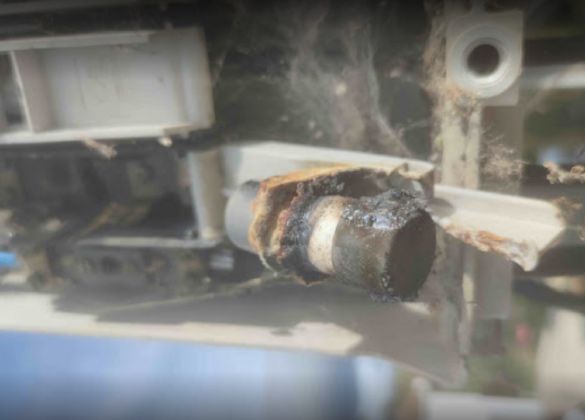 Un primer plano de una tubería oxidada en el costado de un vehículo.