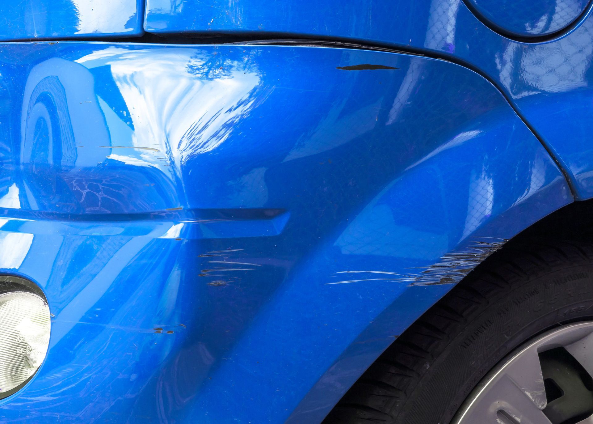 Un primer plano de un coche azul con un parachoques dañado.