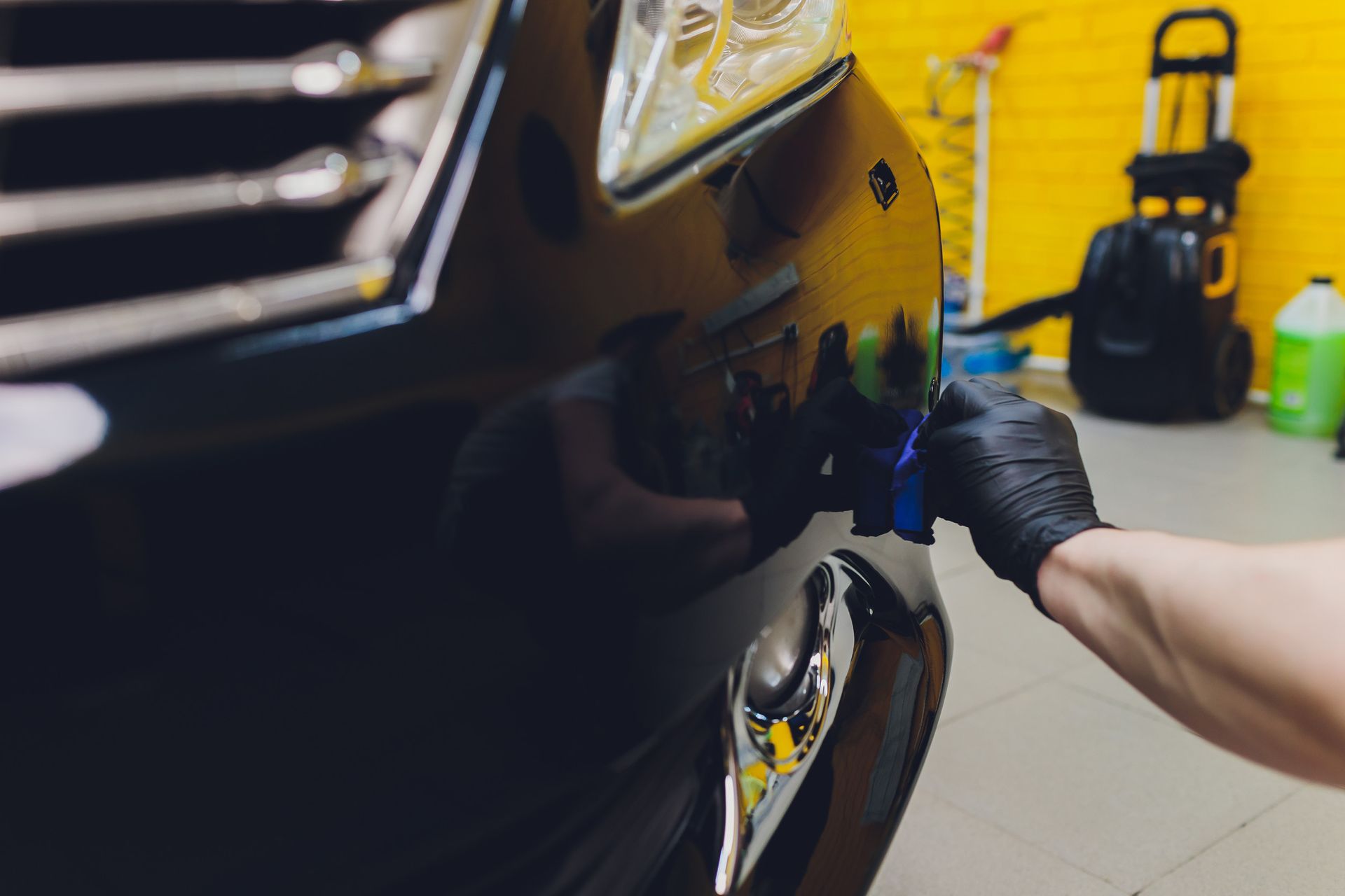 Una persona está puliendo el frente de un automóvil negro.