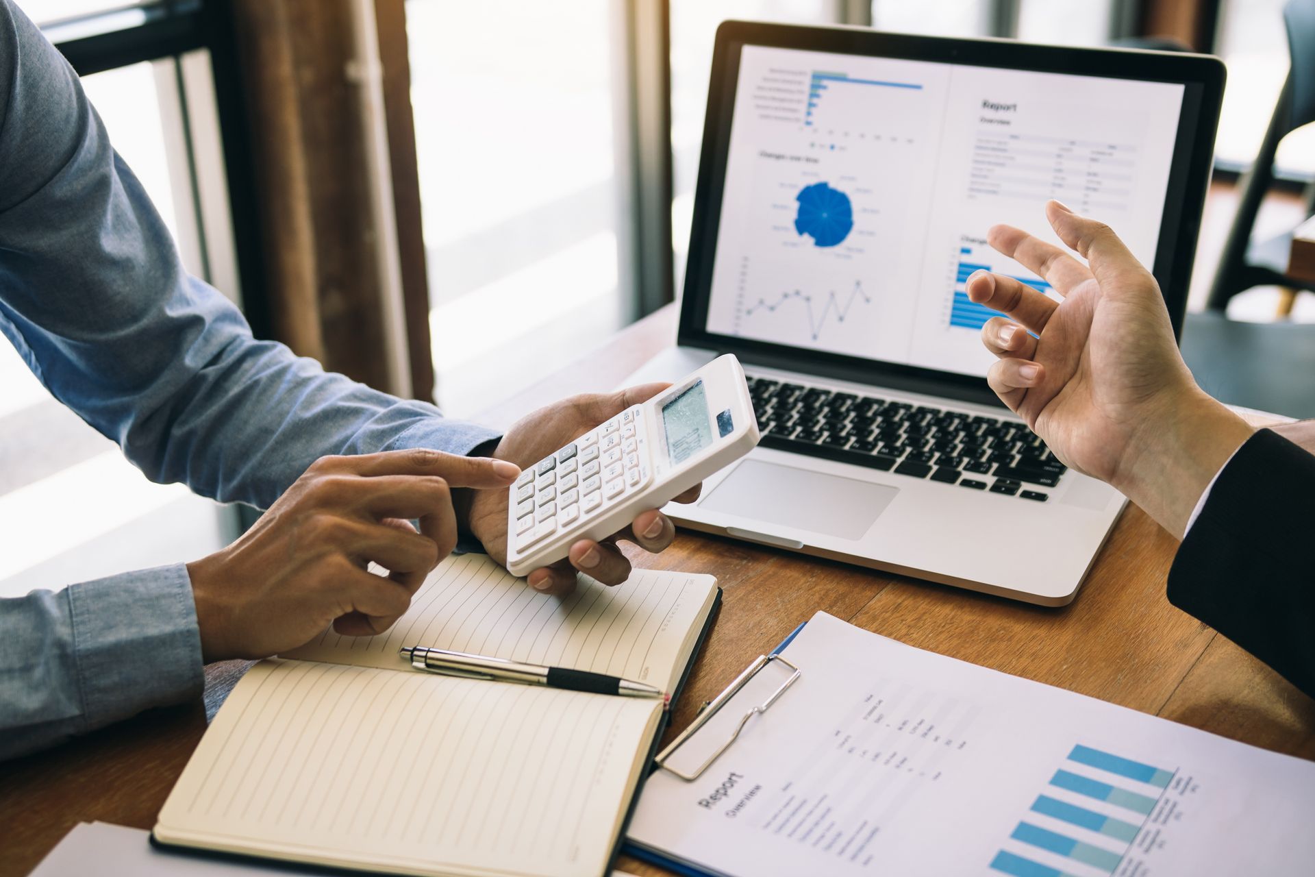 Photo d'un homme tenant une calculatrice à la main et un ordinateur sur la table avec des graphiques