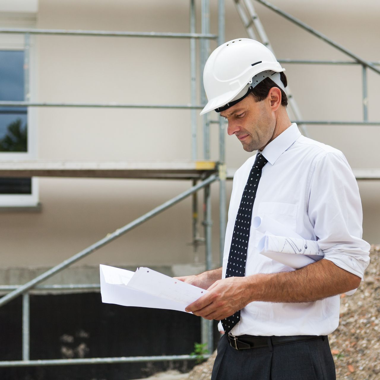 Photo d'un homme avec un casque de chantier devant un immeuble