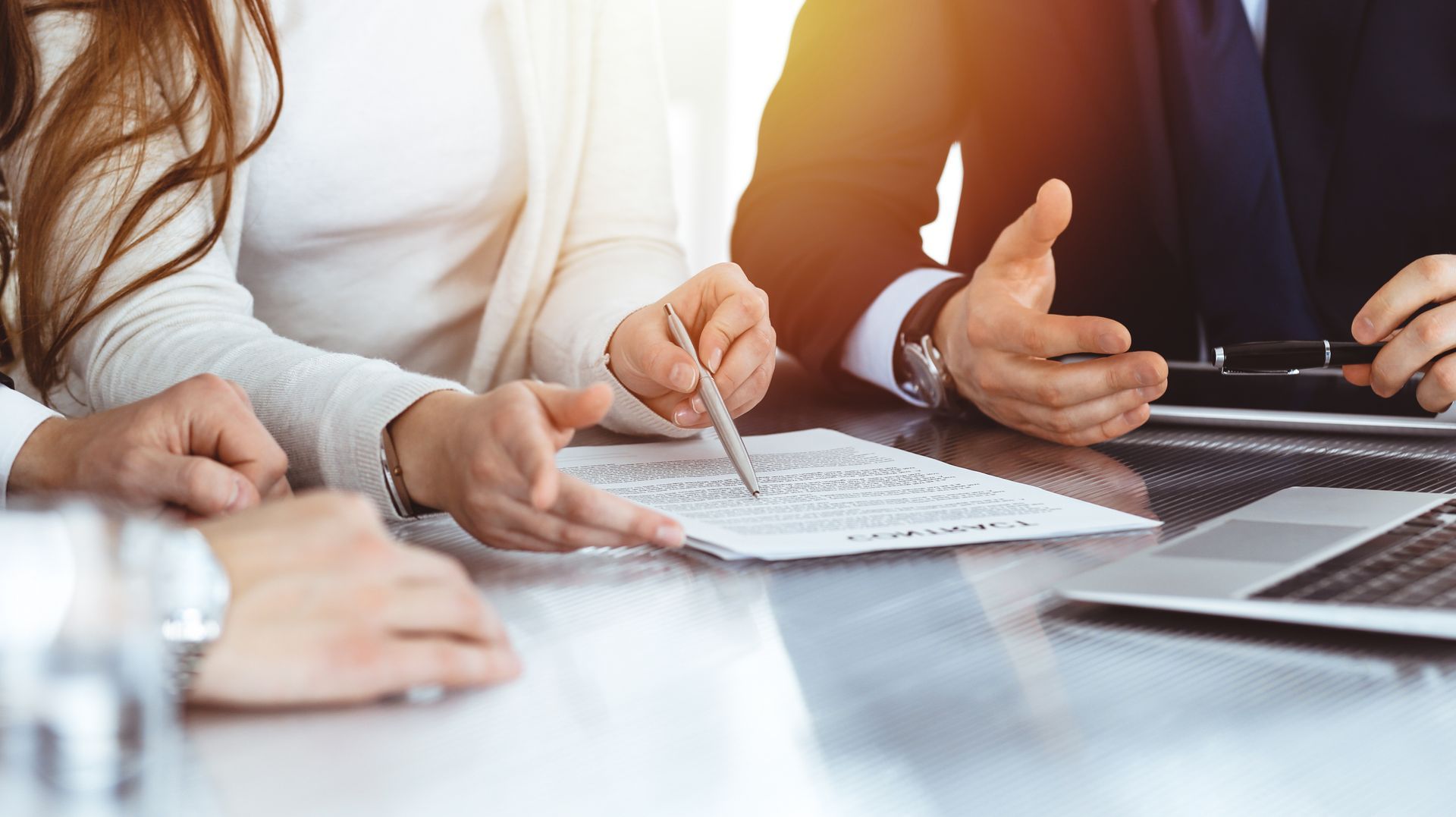 Photo de plusieurs personnes autour d'une table qui lisent un document dont une avec un stylo à la main