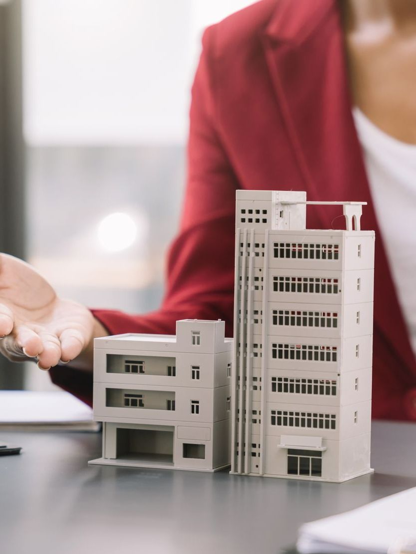 Une femme montre la maquette d'un immeuble sur une table