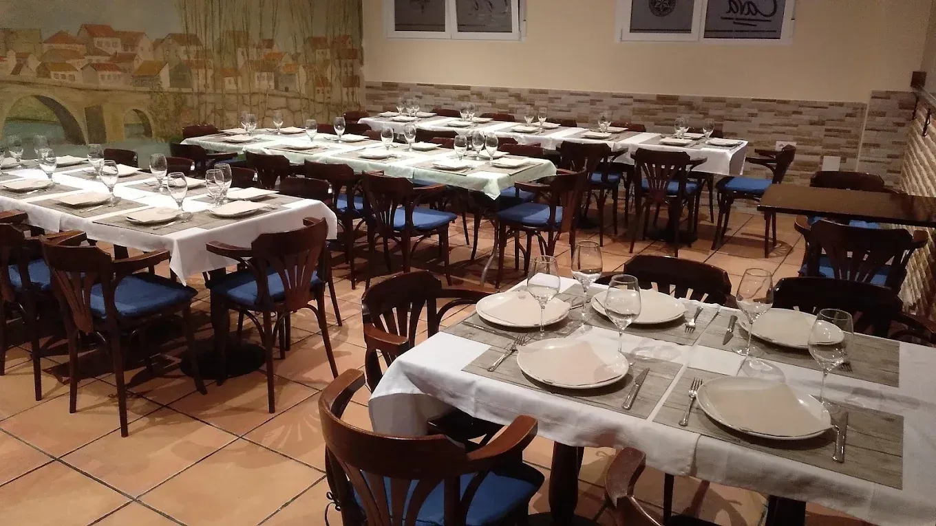 Comedor con mesas y sillas dispuestas, cubiertas con manteles blancos