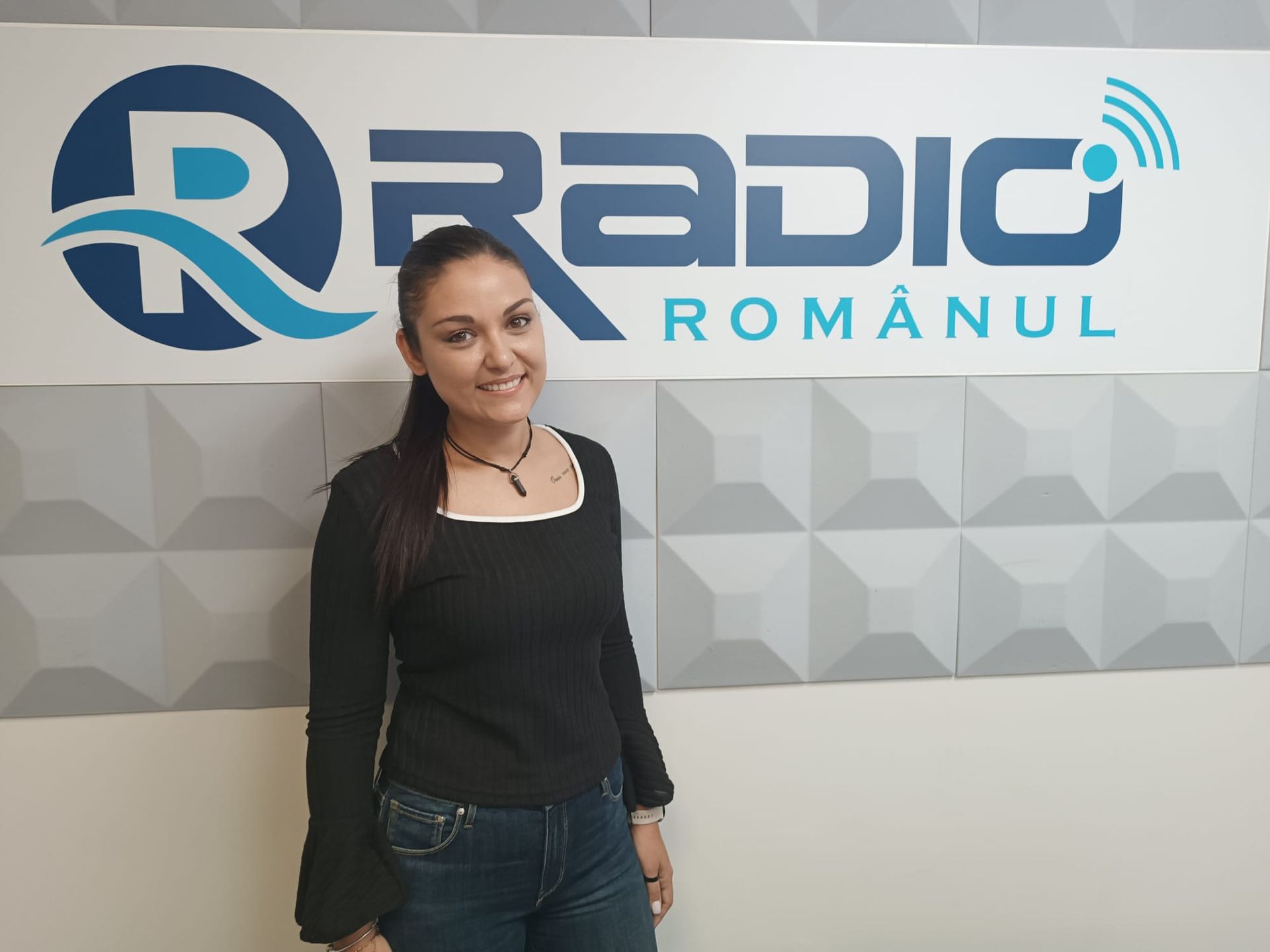 Una mujer está parada frente a un cartel que dice radio romanul
