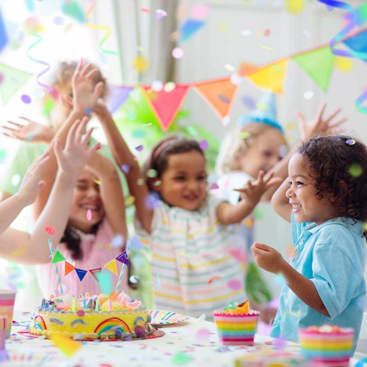 Un grupo de niños están celebrando un cumpleaños con un pastel y confeti.