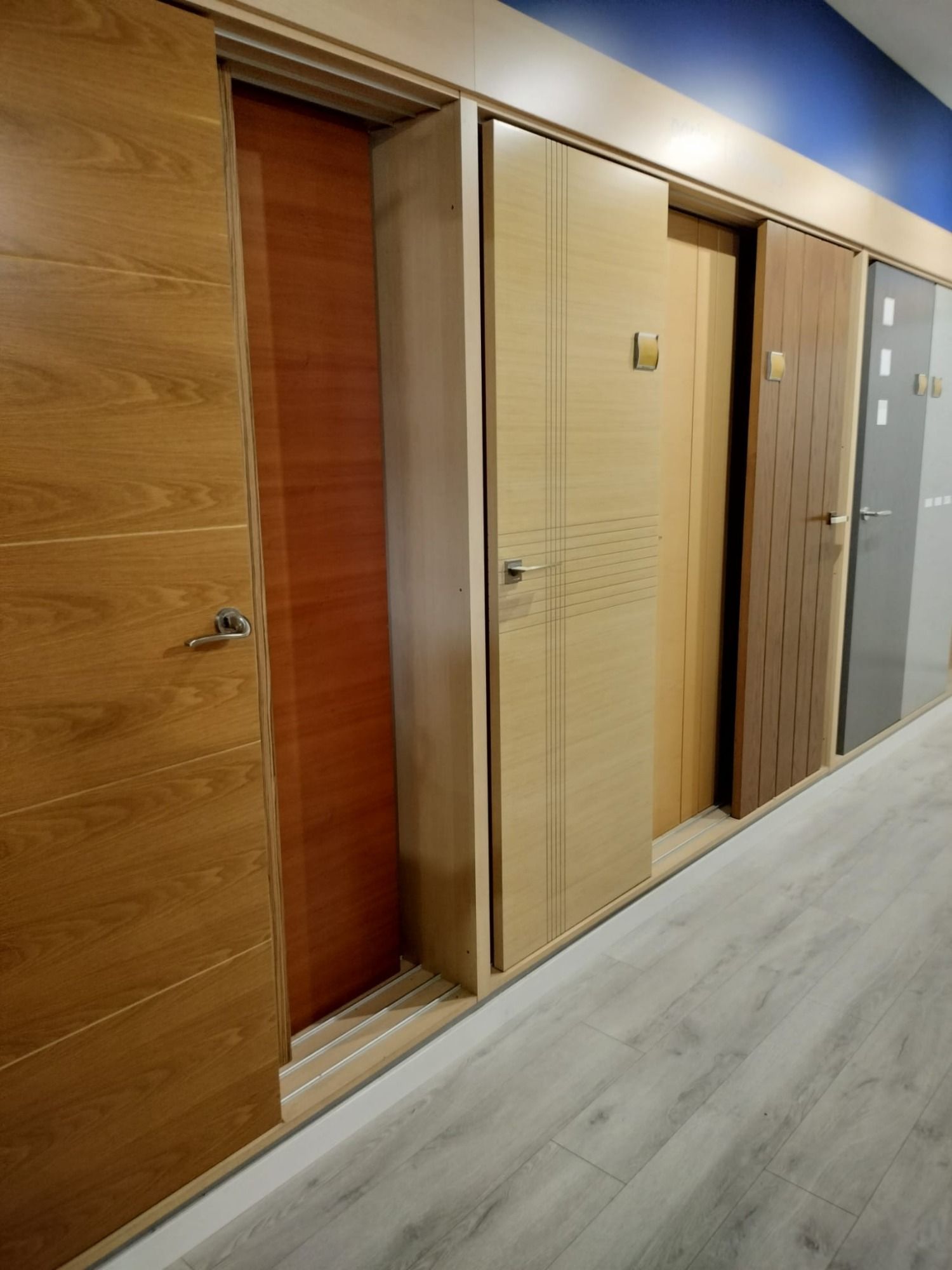 Hilera de puertas interiores modernas en un pasillo, principalmente de madera y con acabados en color beige