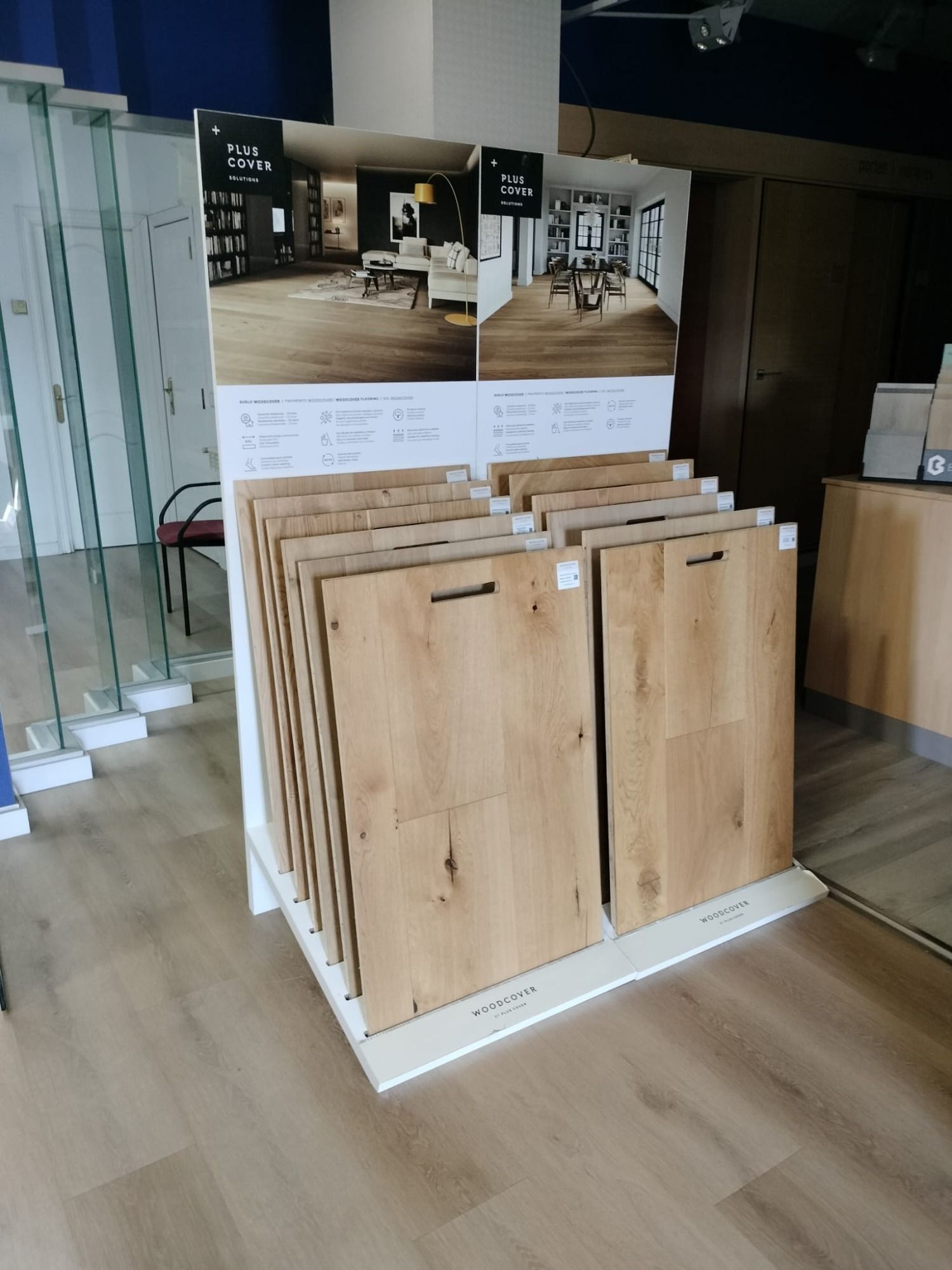 Exposición de muestras de suelos con aspecto de madera en una sala de exposición, con una escalera 