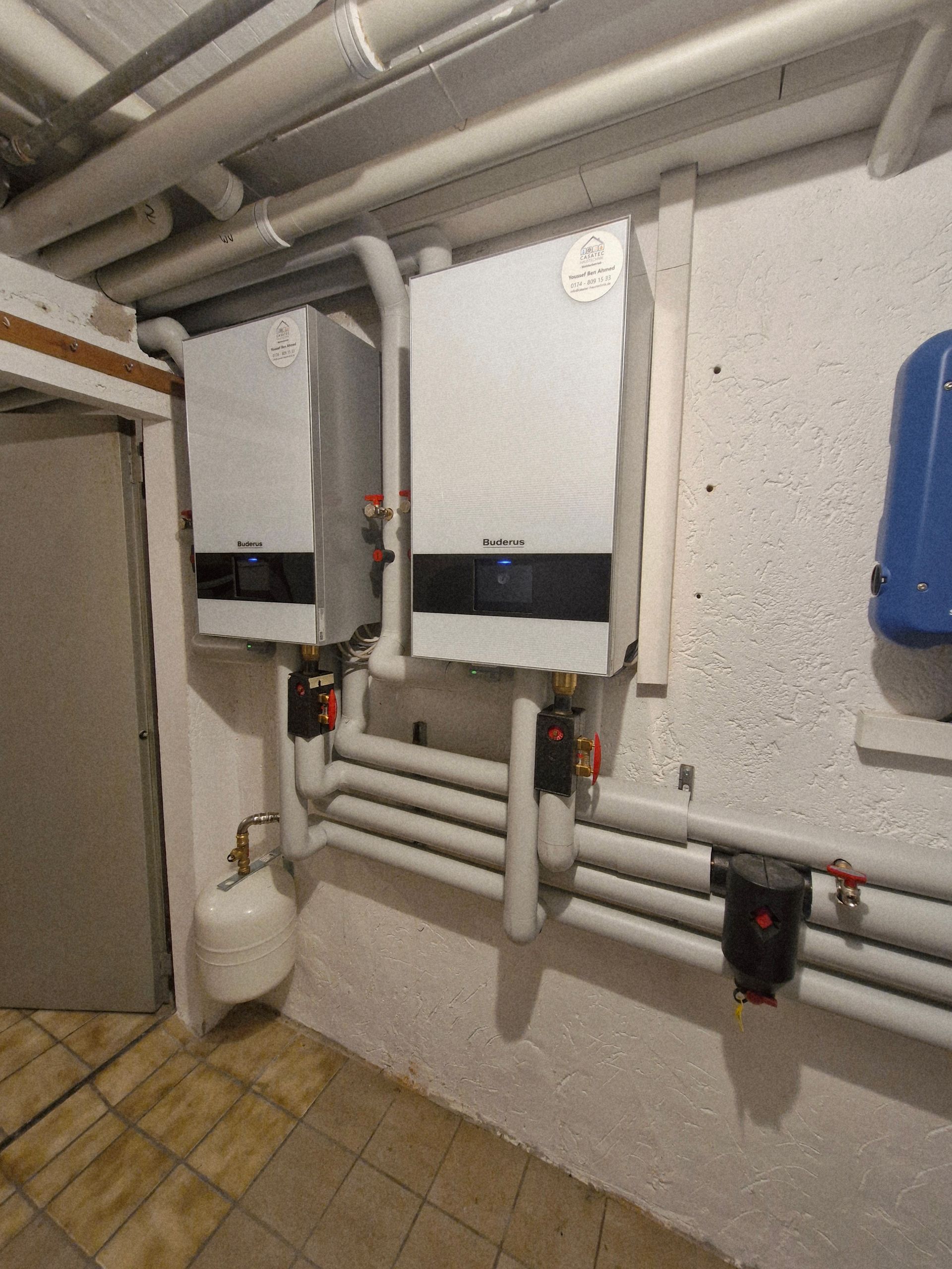 Windrad hinter einer Reihe von Solarmodulen auf einer Wiese unter bewölktem Himmel