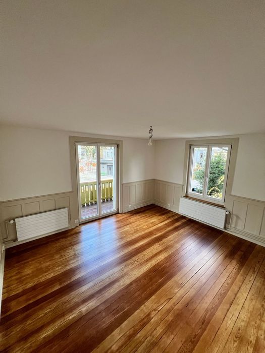 Modernes Wohnzimmer mit an der Wand montiertem Fernseher, weisser Konsole, Lautsprechern und Topfpflanzen