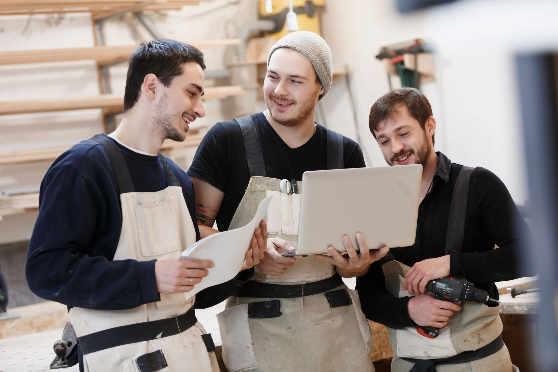 Une équipe d'artisans debouts discutant entre eux devant un ordinateur
