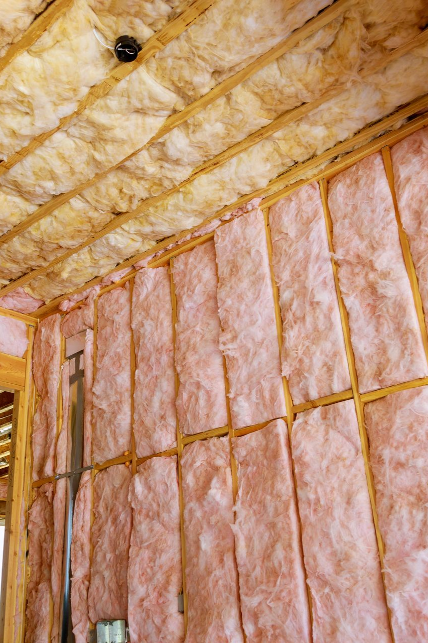 Isolation rose installée entre les montants en bois d'un plafond et d'un mur.