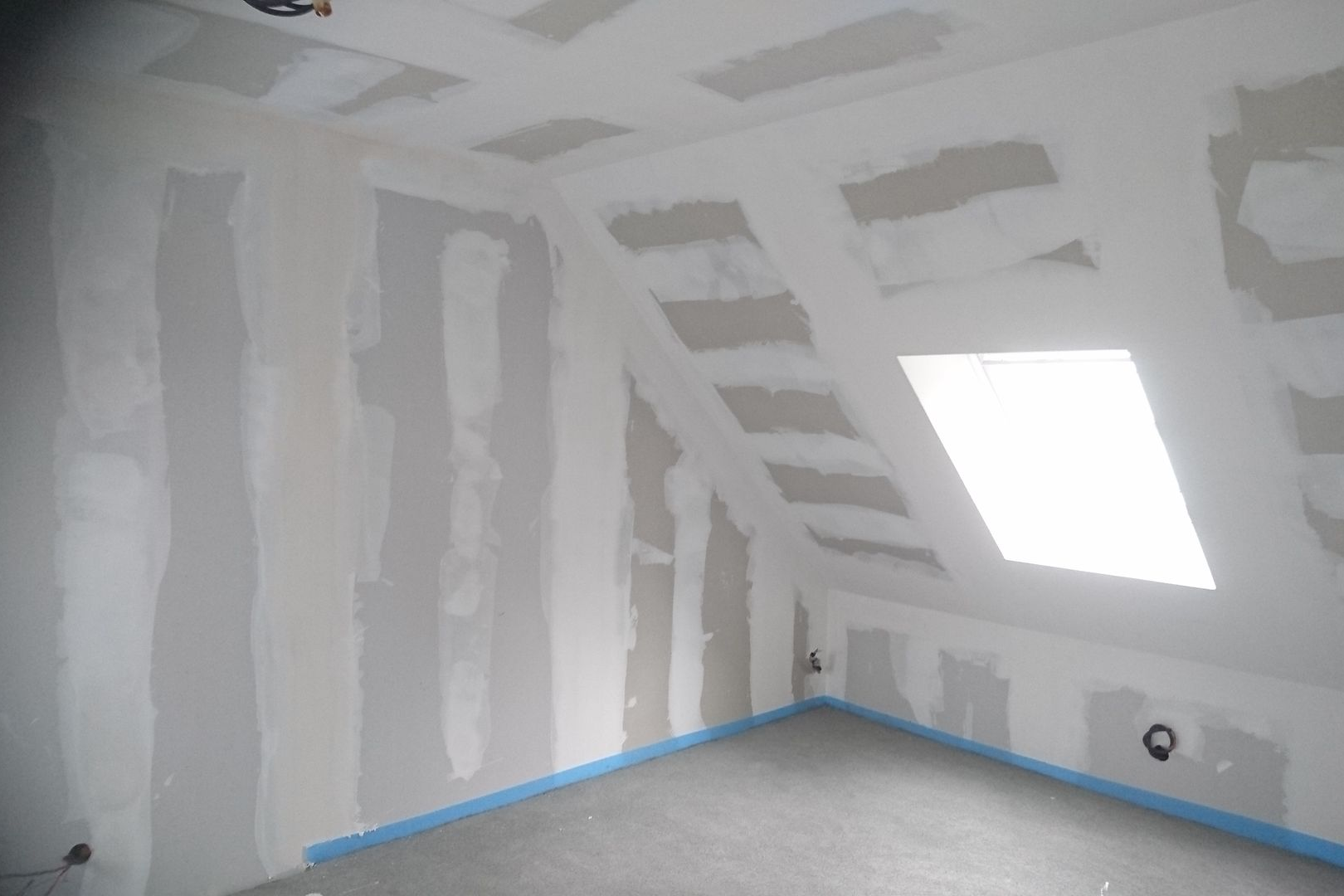 Intérieur d'une pièce en construction avec cloisons sèches et murs en angle ; puits de lumière.