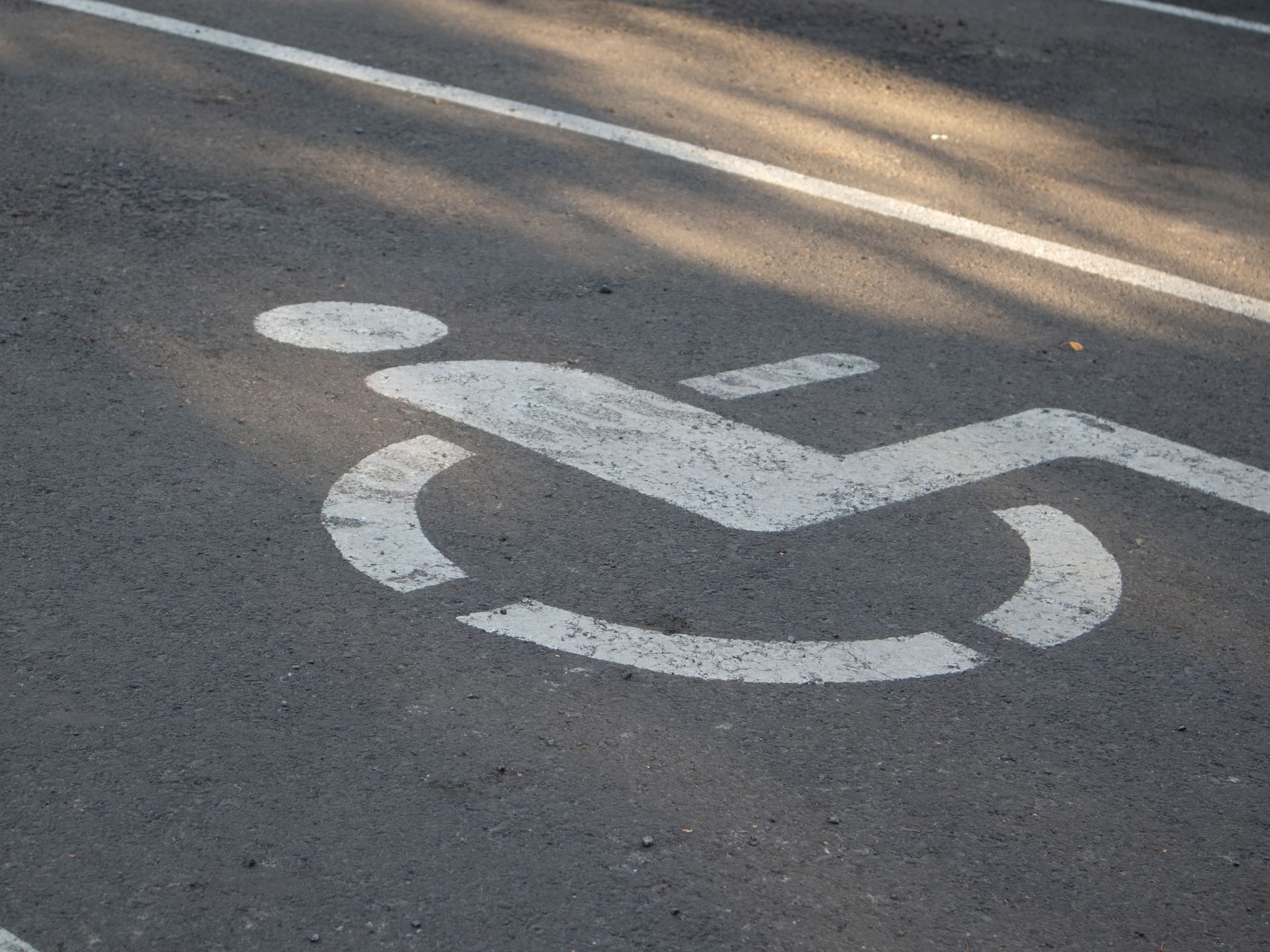 Symbole handicapé blanc peint sur l'asphalte.