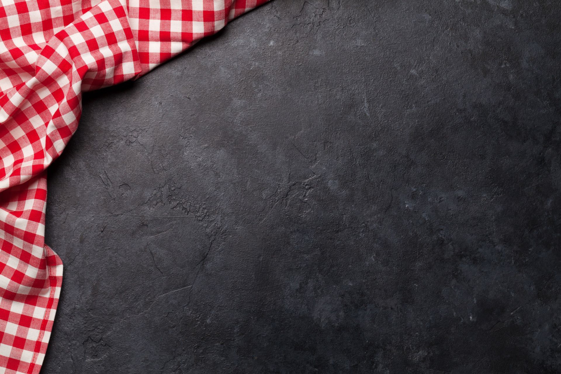 Tissu à carreaux rouges et blancs sur une surface texturée gris foncé.
