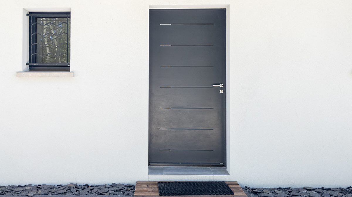 Habitation blanche avec une porte d'entrée anthracite en aluminium