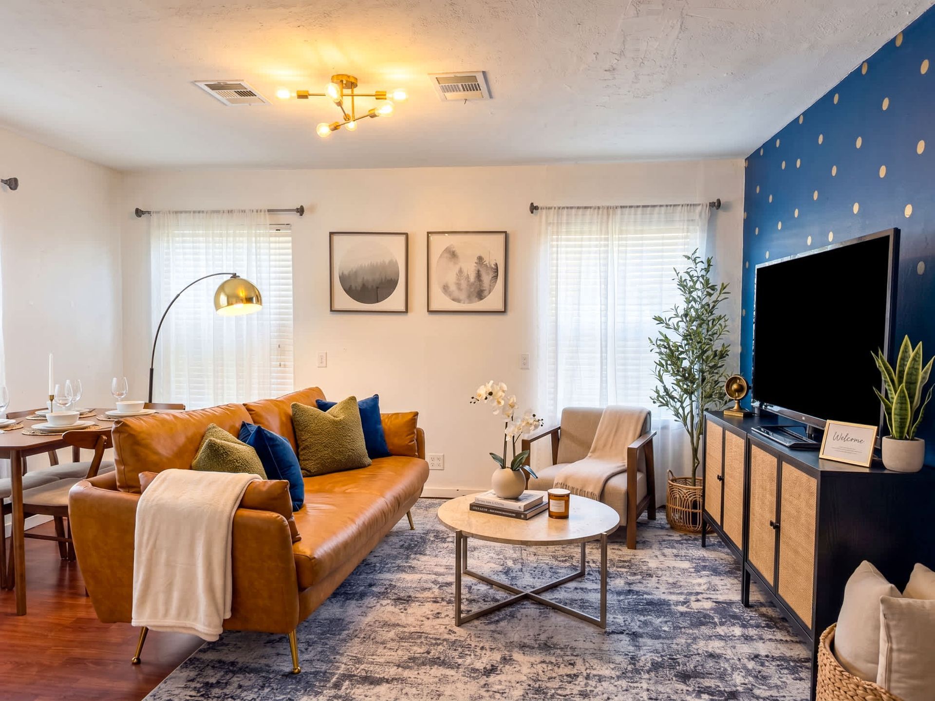Cozy living room with tan sofa, blue accent wall, round coffee table, TV, and soft lighting