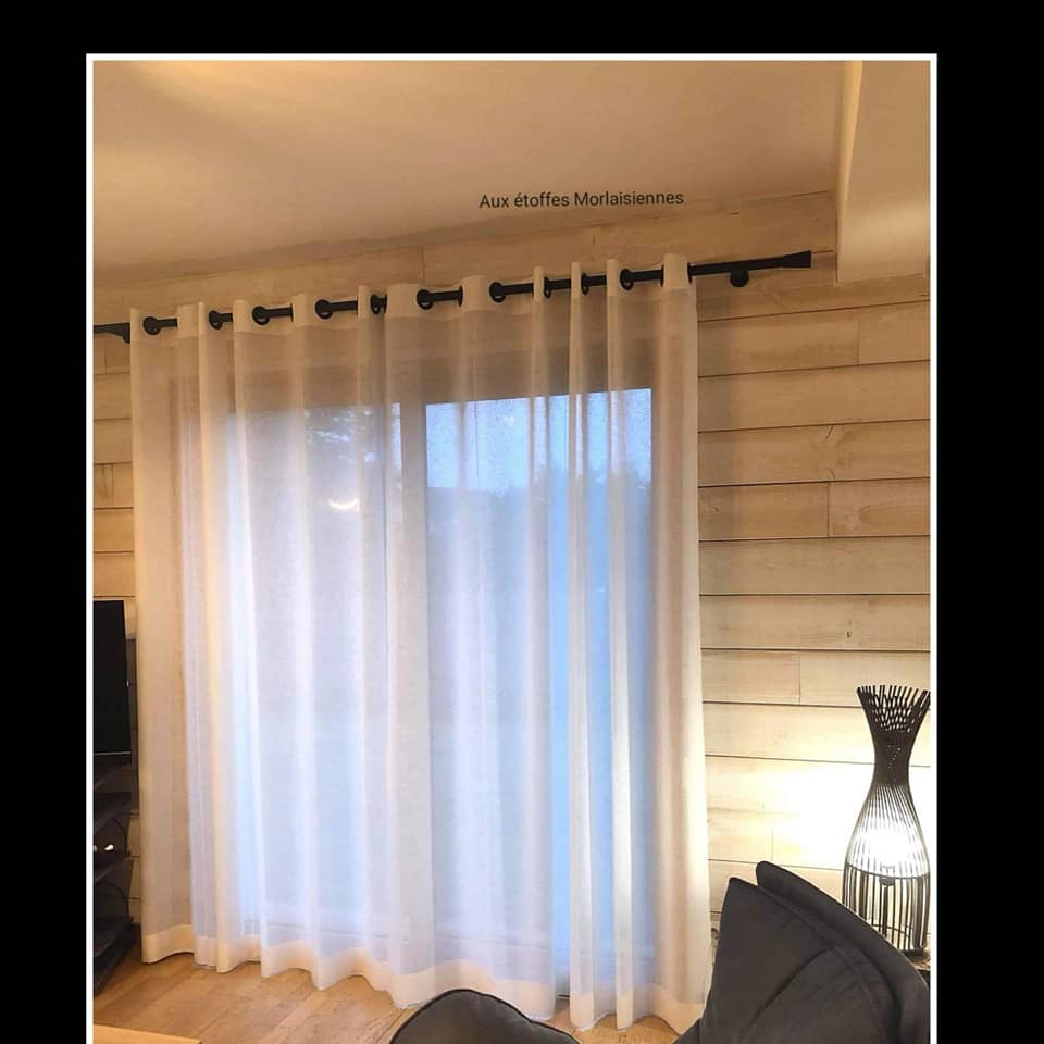 Voilage blanc uni installé dans une maison aux murs en bois
