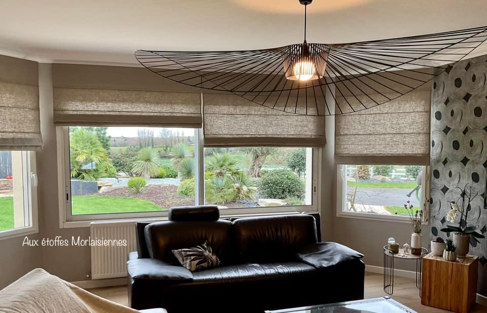 Plusieurs stores bateaux gris partiellement fermés dans un salon