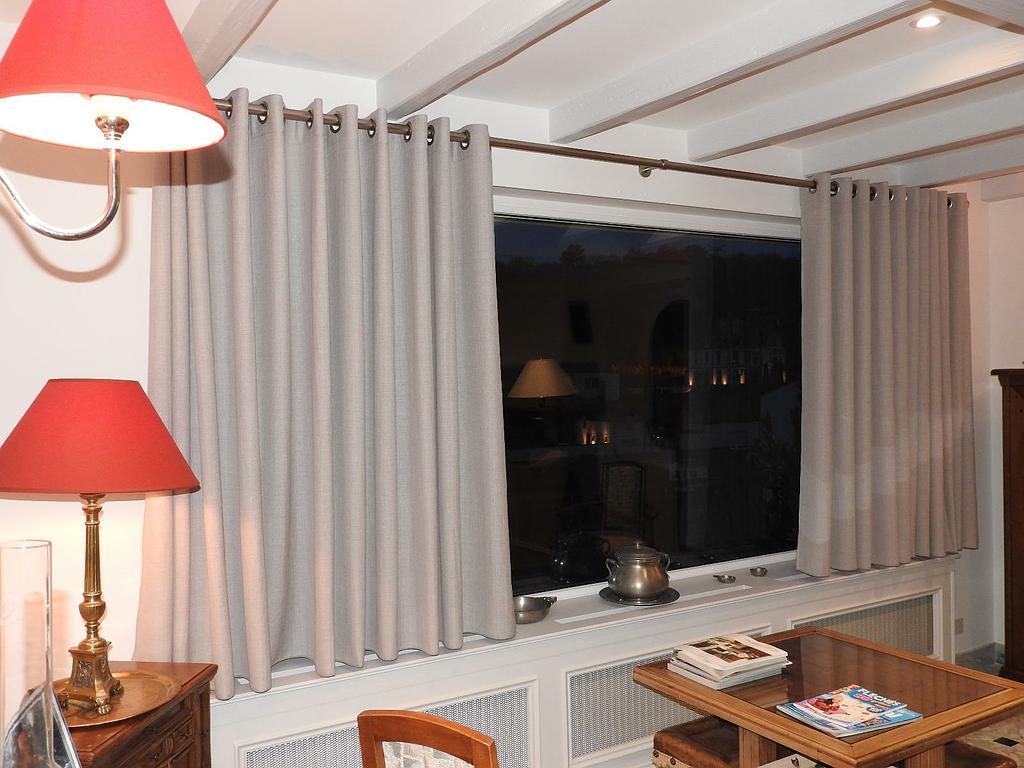 Doubles rideaux gris sur une grande baie vitrée derrière un canapé blanc