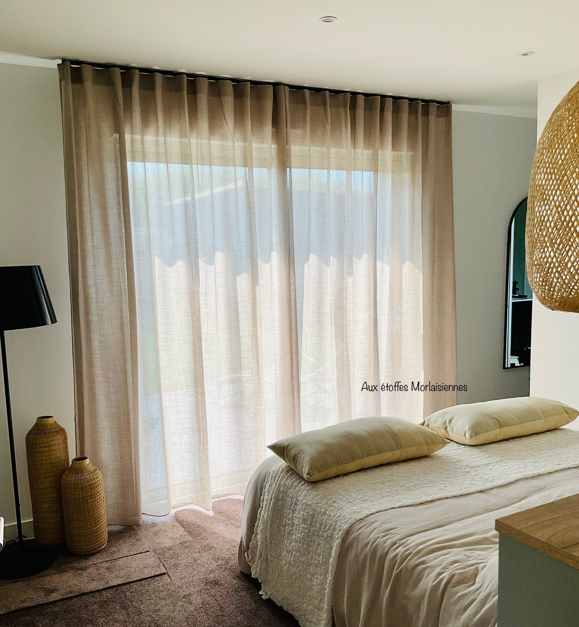 Voilage gris dans une chambre sur une fenêtre en face d'un lit