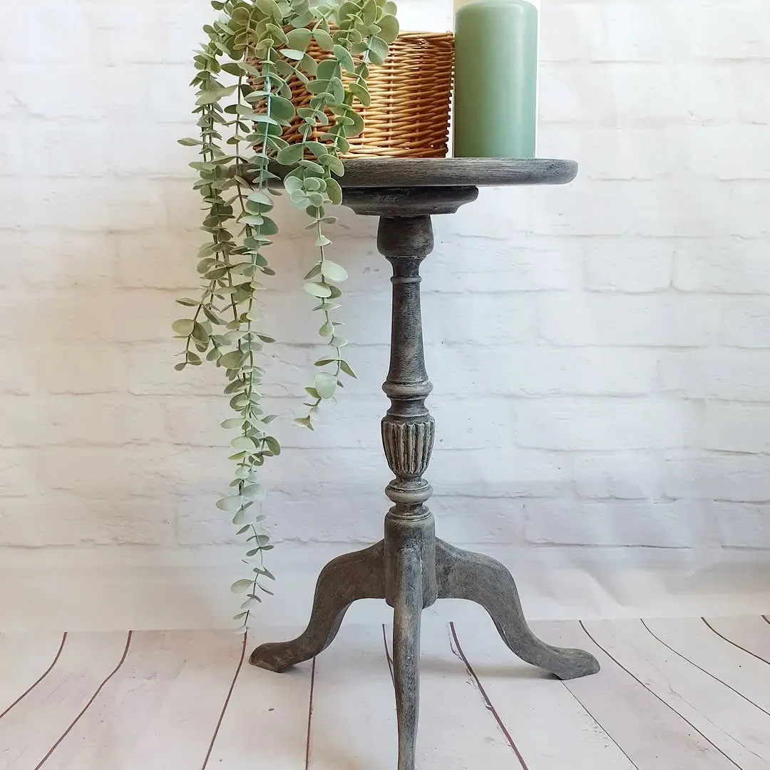 Macetero adornado de color gris con una planta en maceta, una vela y una canasta