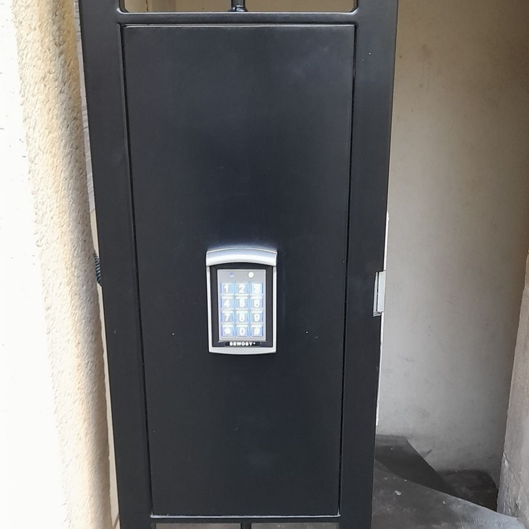 Porte de sécurité en métal noir avec clavier numérique clair monté au centre.
