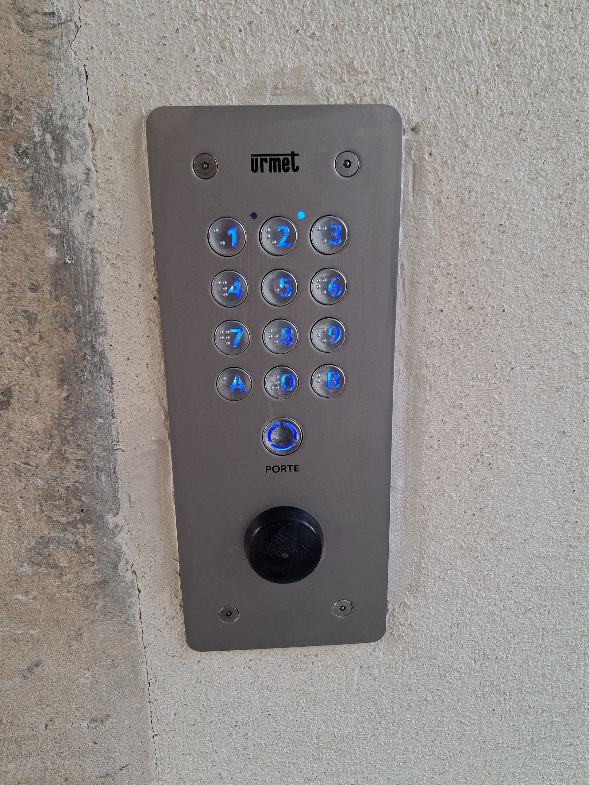 Un interrupteur double mural gris avec un cache de protection, installé sur un mur texturé de couleur claire.