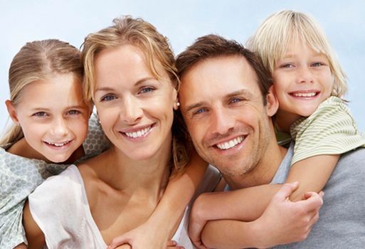 Una familia posa para una fotografía y sonríe para la cámara.