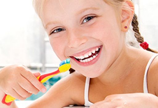 Una niña se cepilla los dientes con un cepillo de dientes colorido.