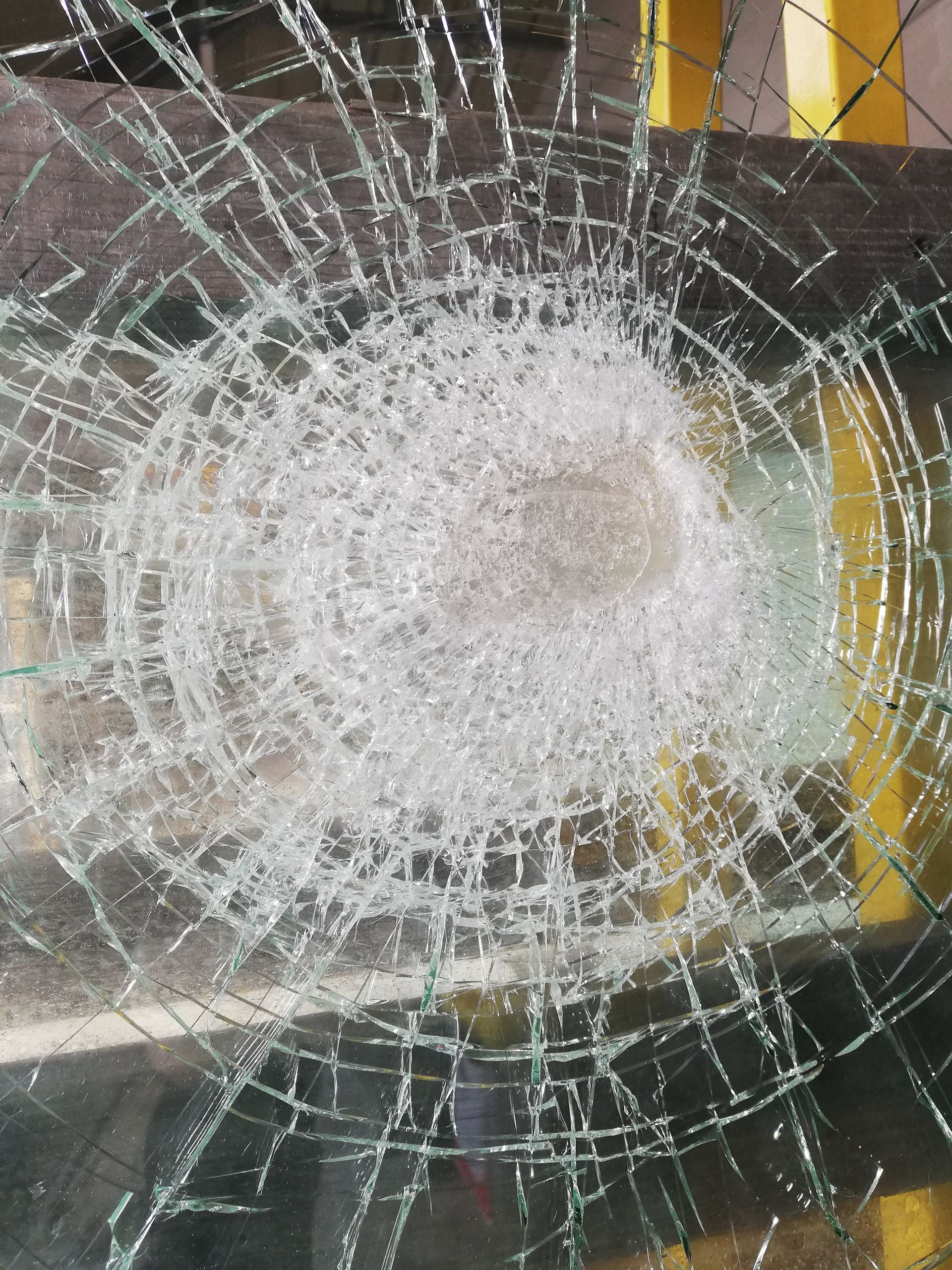 Vitre brisée avec un point d'impact central et des fissures rayonnantes.