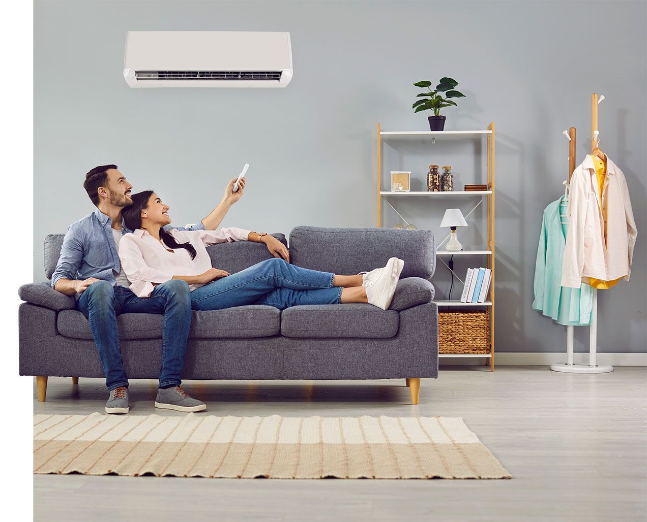 Couple dans un canapé qui règle le climatiseur à l'aide d'une télécommande