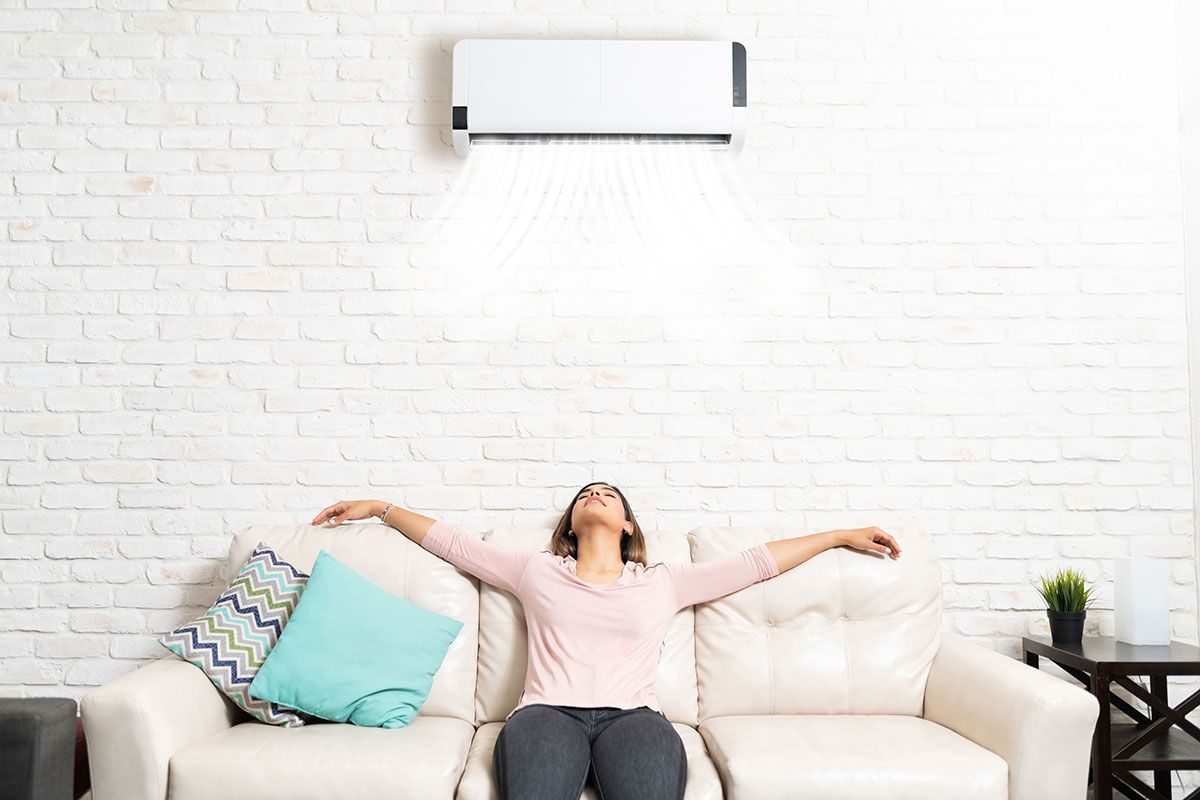 Femme dans son canapé qui profite de sa climatisation réservible