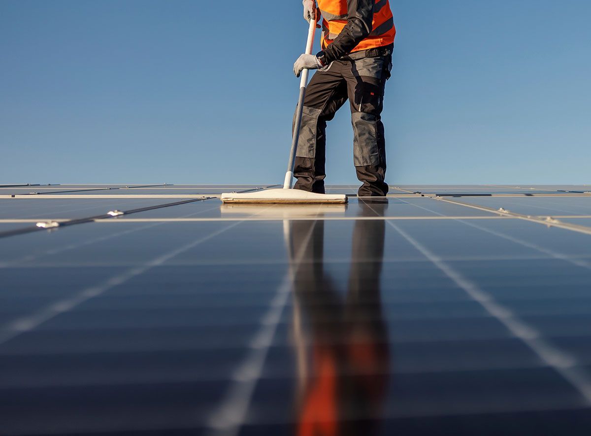 Homme qui nettoie des panneaux solaires avec un balai-brosse