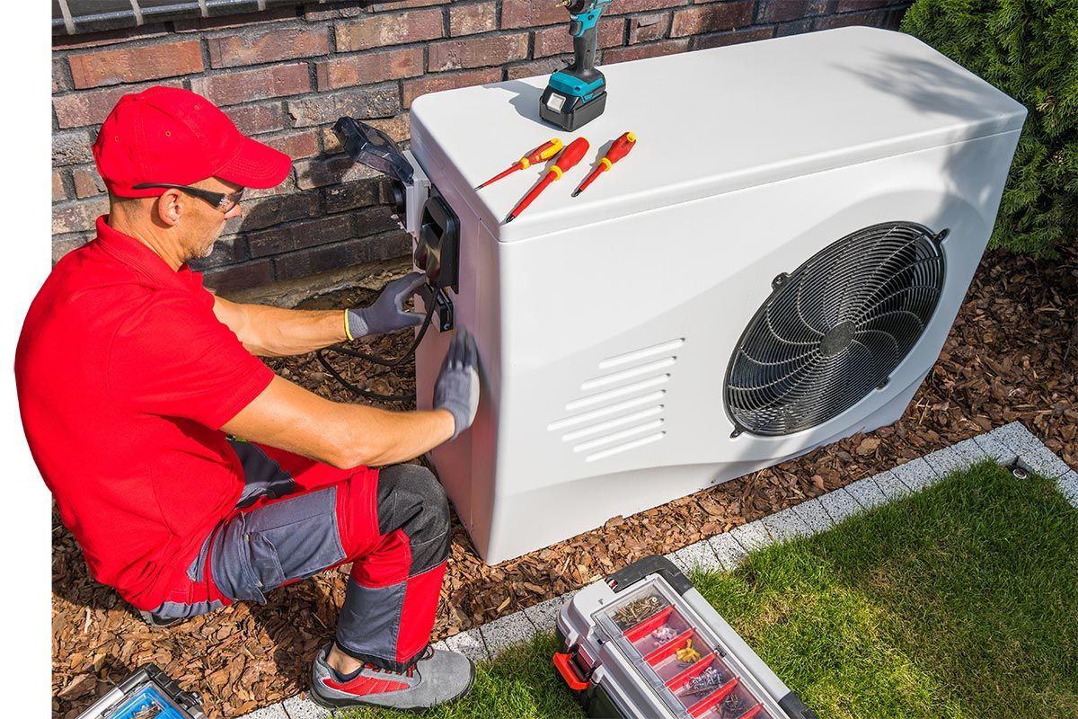Technicien qui répare une pompe à chaleur avec ses outils