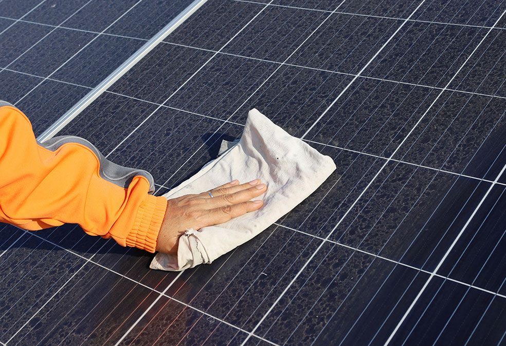 Zoom sur une main qui passe le chiffon sur un panneau solaire
