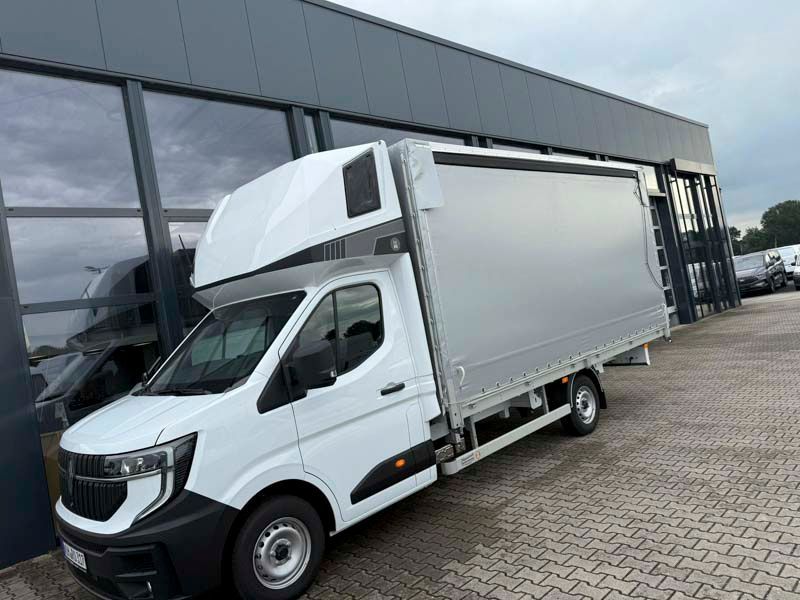 Weißer Lieferwagen mit überdachter Ladefläche, der vor einem Gebäude geparkt ist.